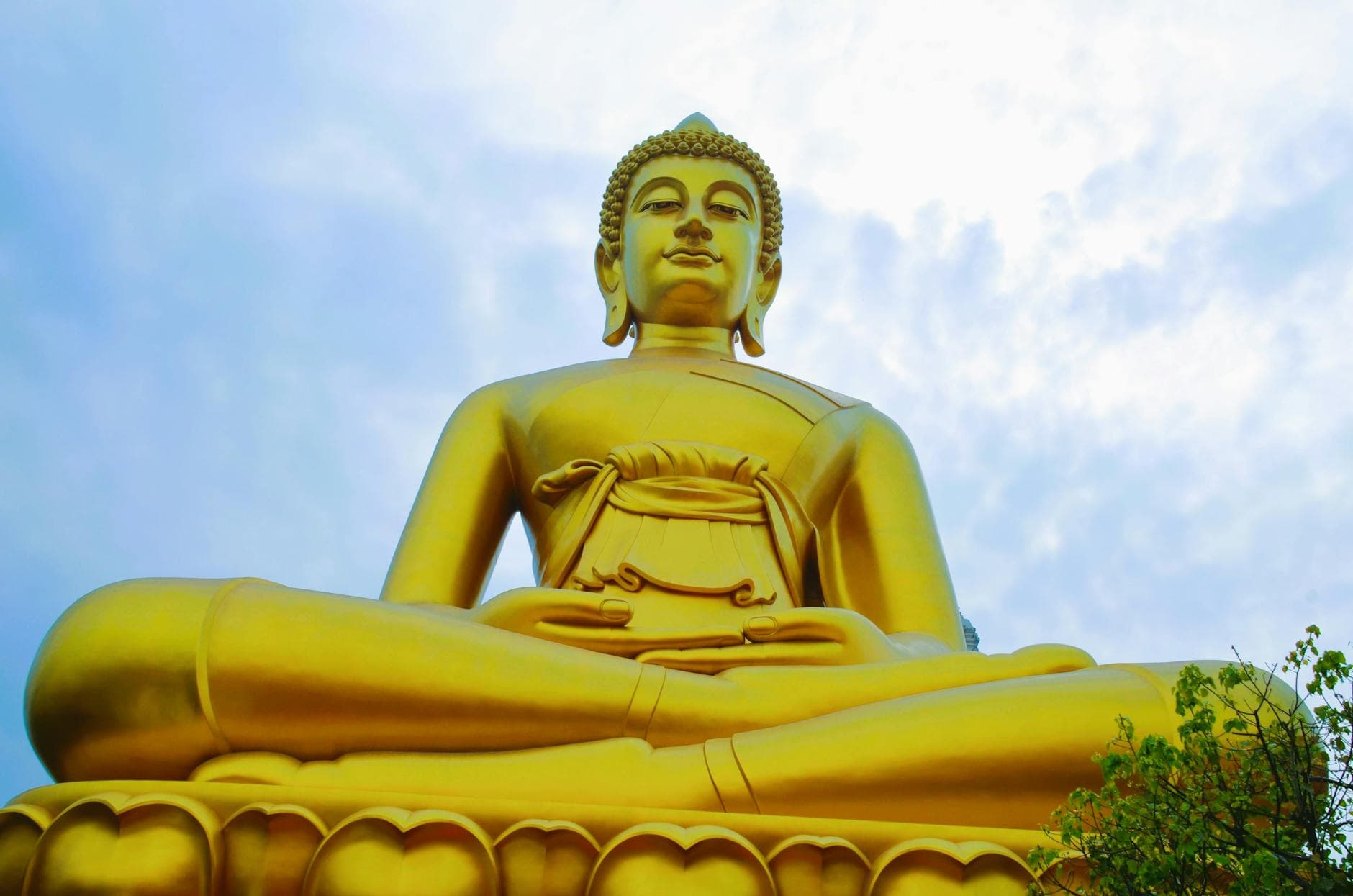 Majestic golden Buddha statue photographed under a bright sky, emphasizing serenity and peace.