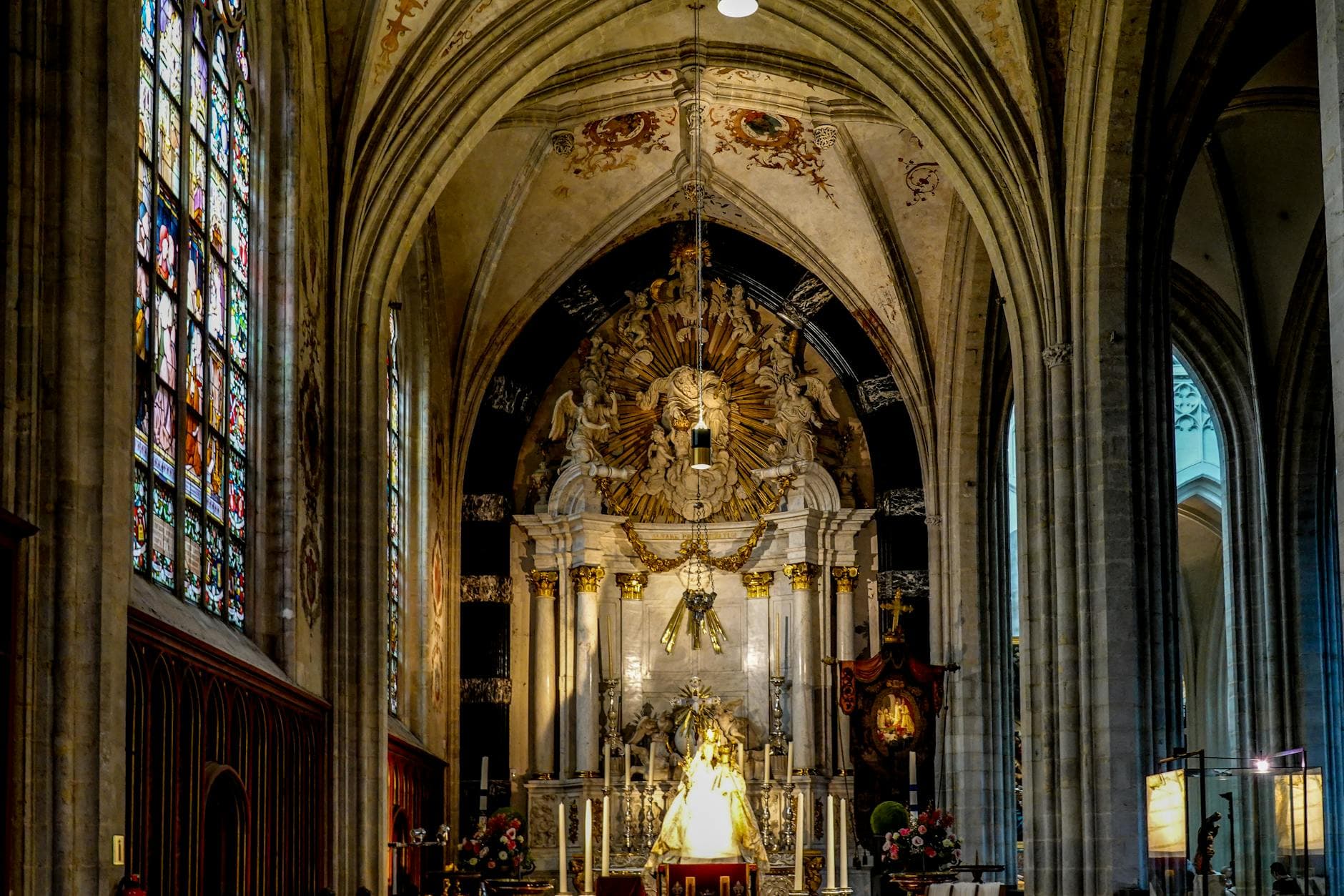 Stunning interior of a Gothic cathedral featuring a beautifully ornate altar and stained glass windows.