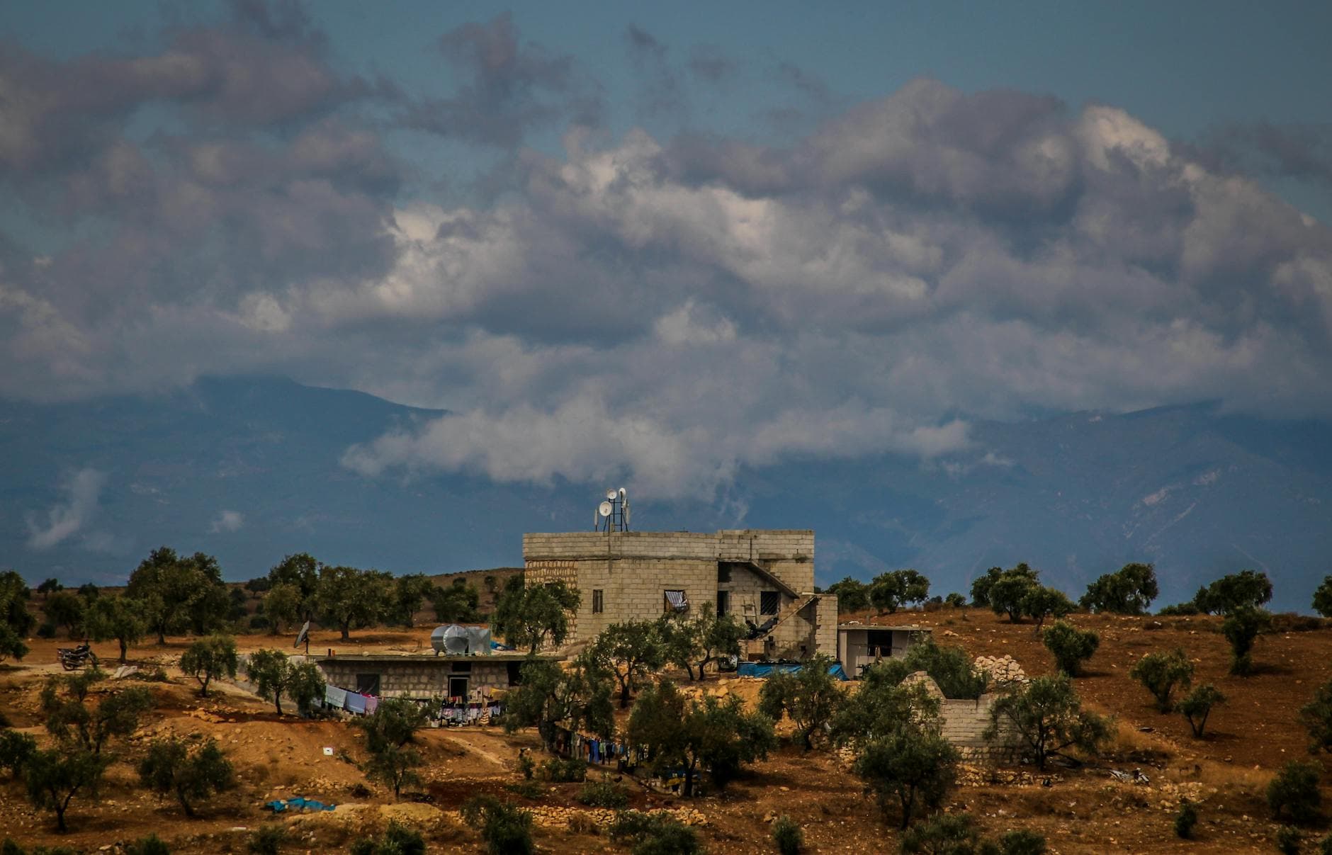 Rural scene in Aaqrabâte, Syria featuring a stone building amidst an expansive landscape.
