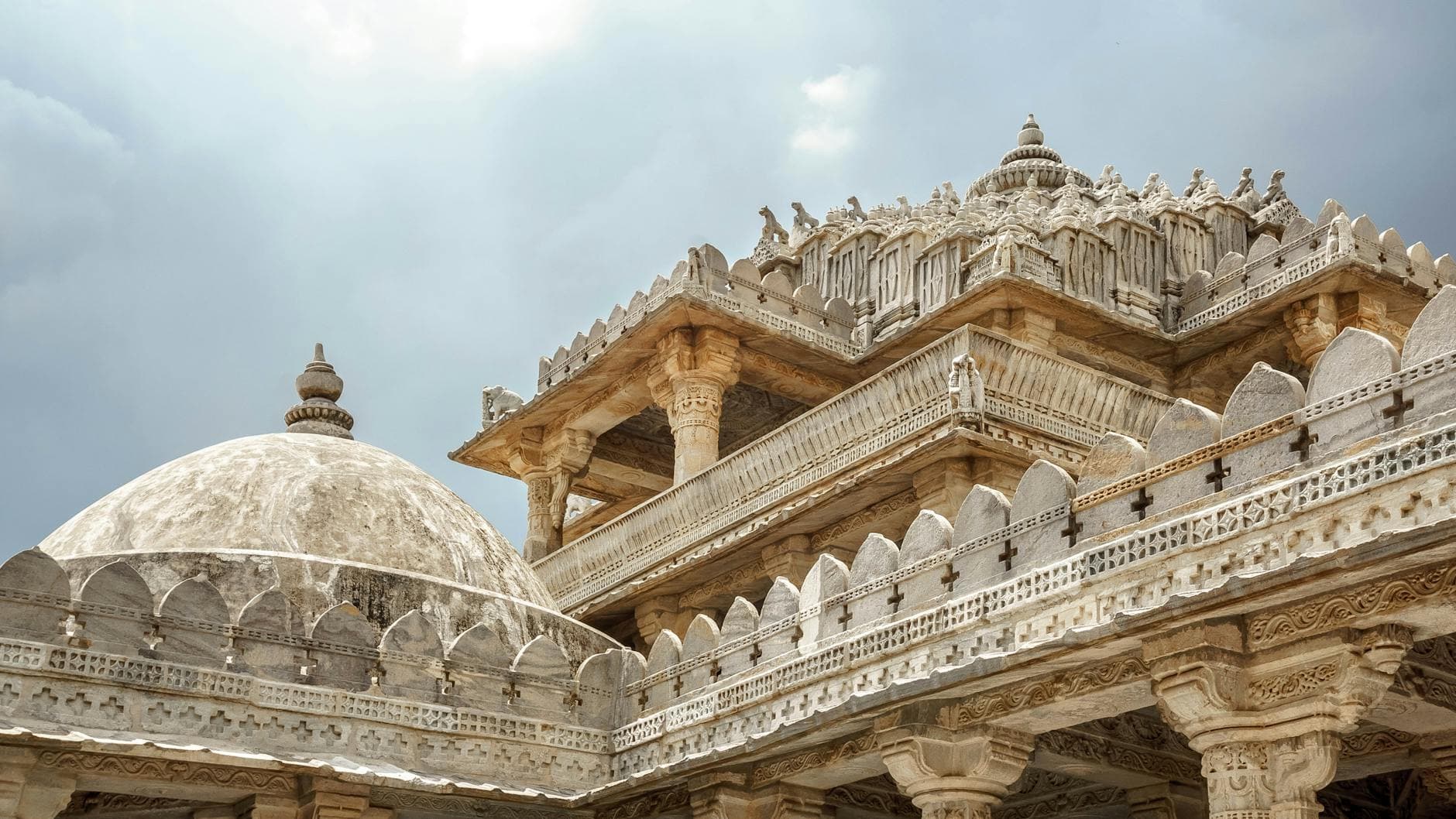 Stunning view of the intricate carvings on the Ranakpur Jain Temple in Rajasthan, India, under a cloudy sky.