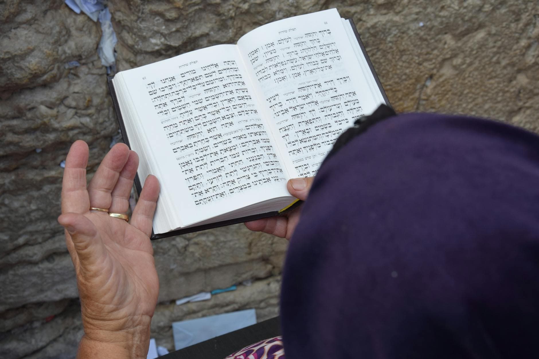Senior woman reading Hebrew text at the Western Wall in Jerusalem, Israel.