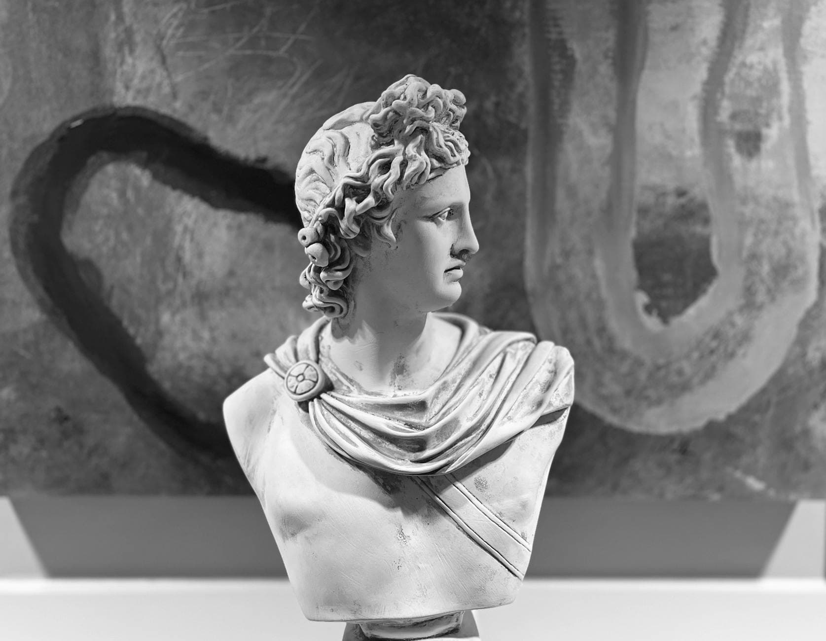 Black and white photo of a classical marble bust with abstract background.