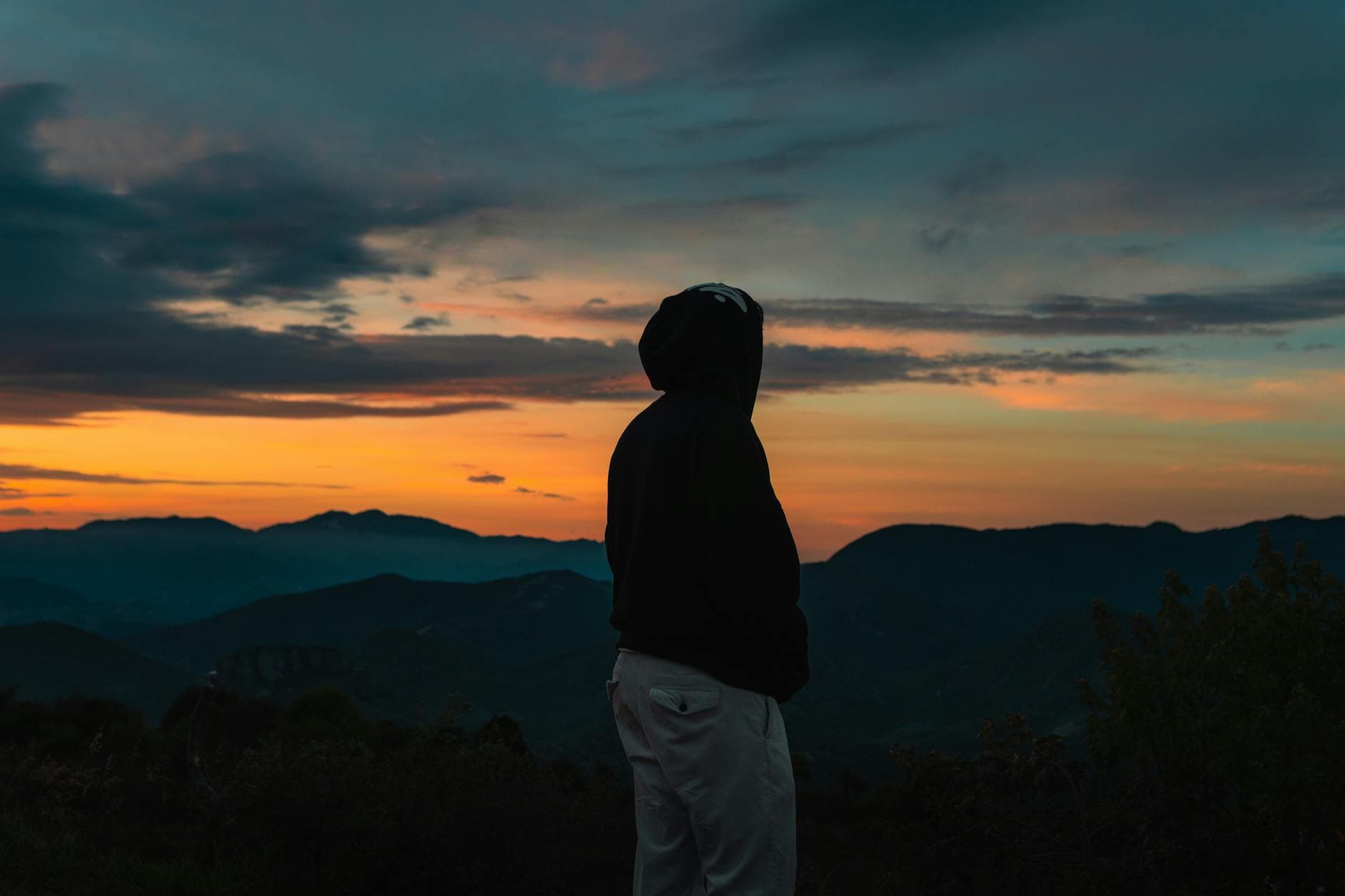 Silhouetted figure in a hoodie watches the sunrise over mountains in Oaxaca, Mexico.