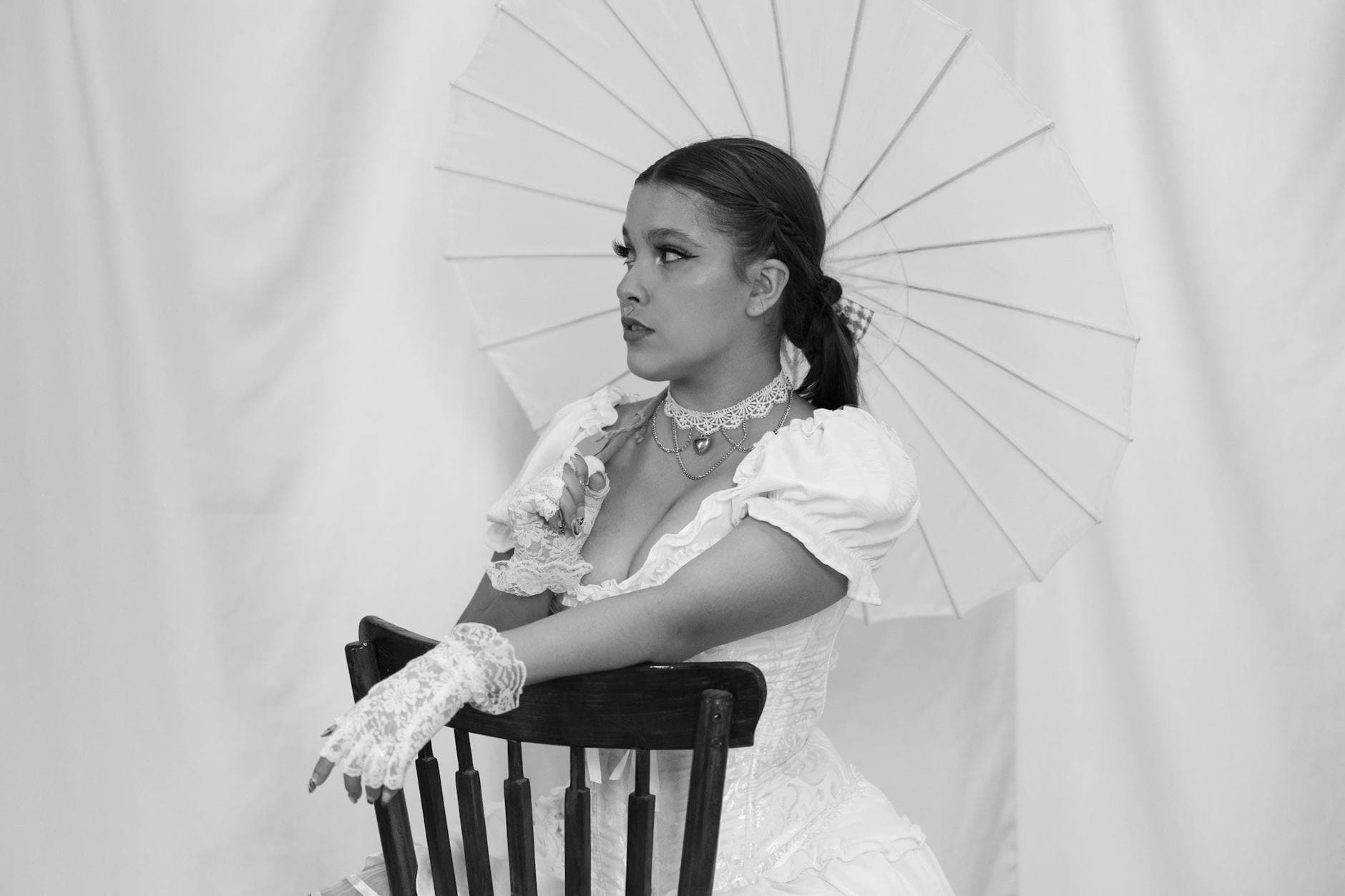 Elegant woman in a Victorian dress holding a parasol in a vintage black and white portrait.