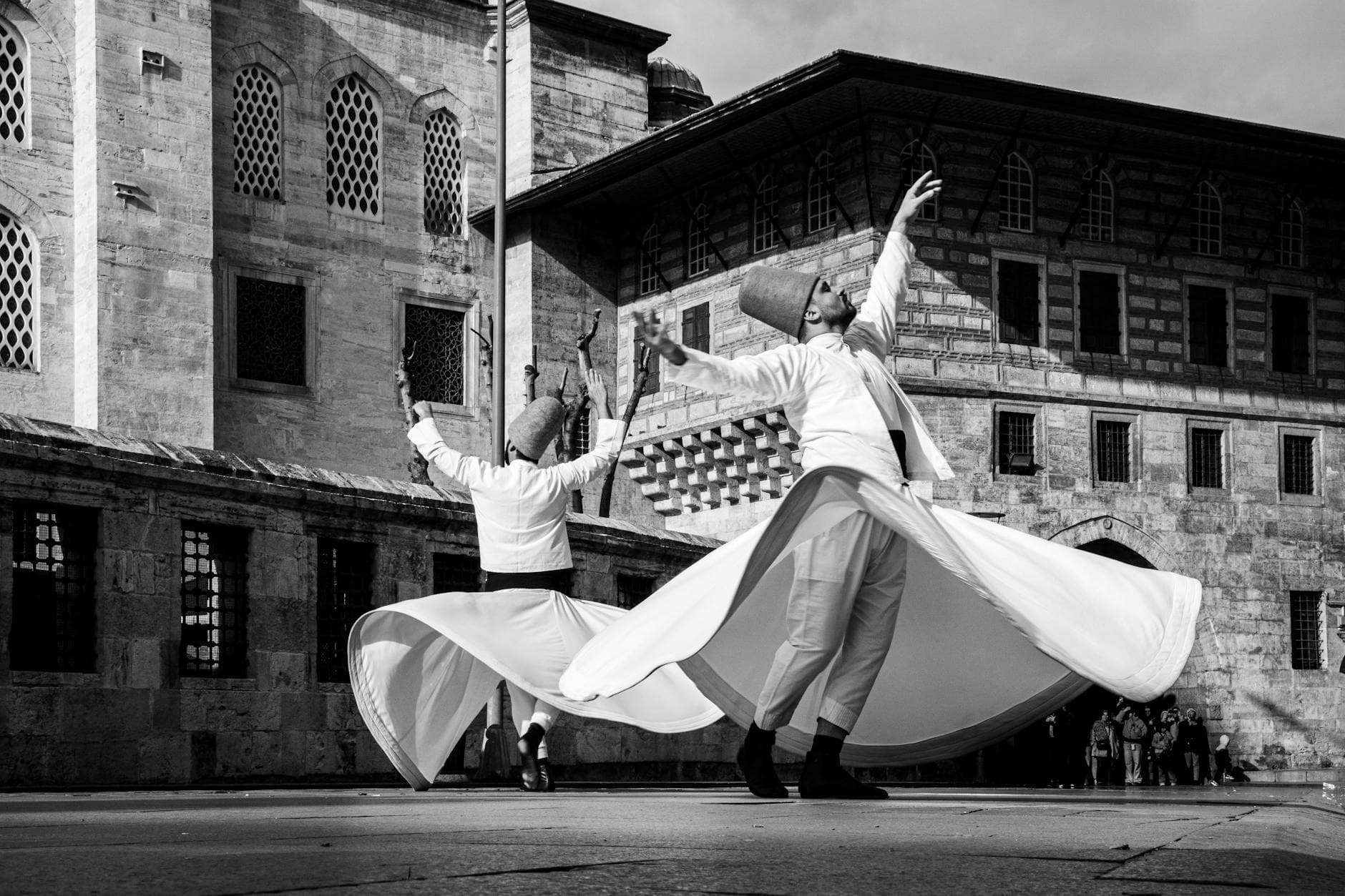 Black and white photo of whirling dervishes spinning at a historic mosque in Istanbul, Türkiye.