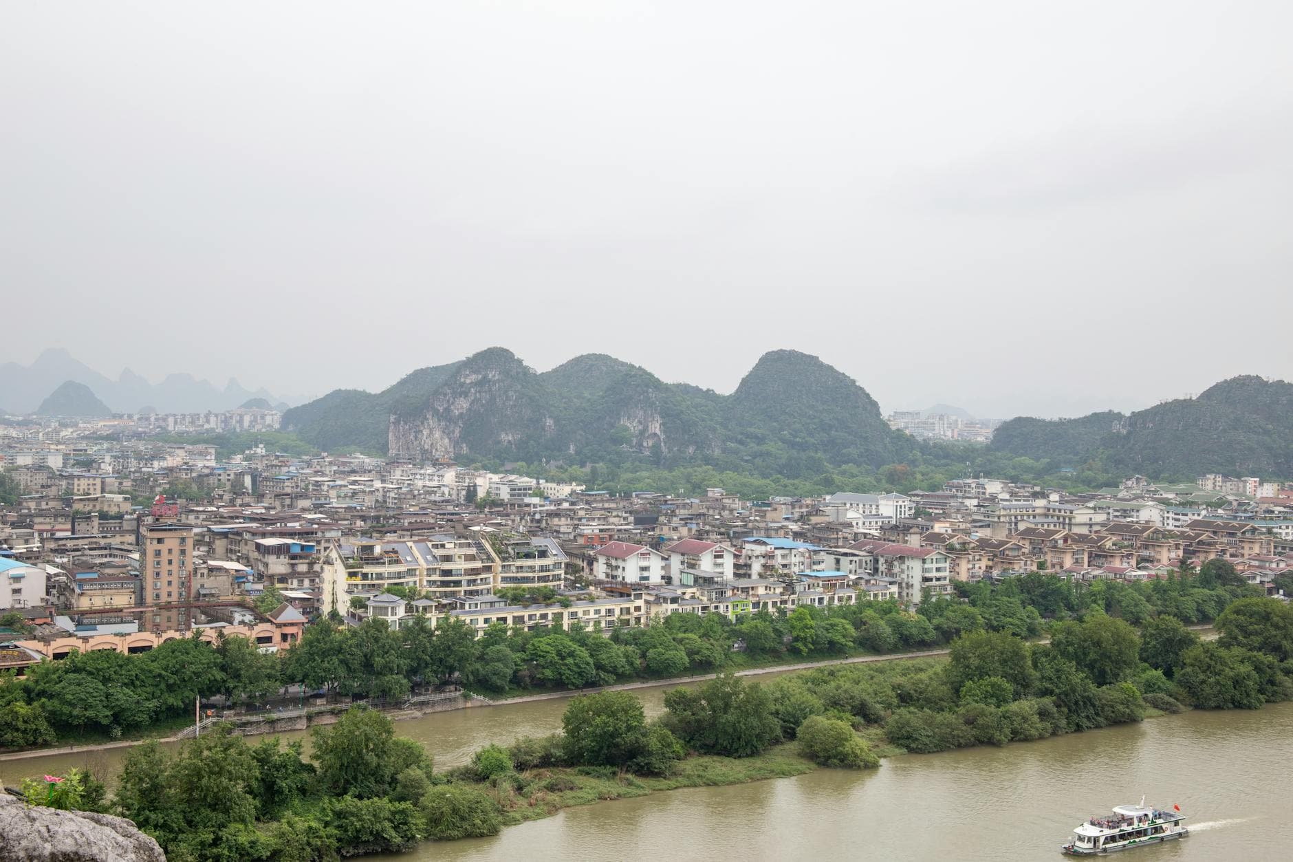 Aerial view of a Chinese town surrounded by lush landscapes and a river.